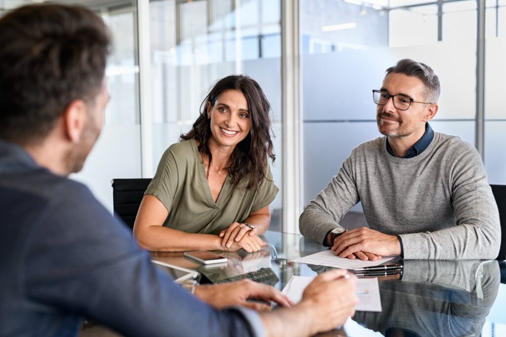 Three people sitting at a desk with paperwork