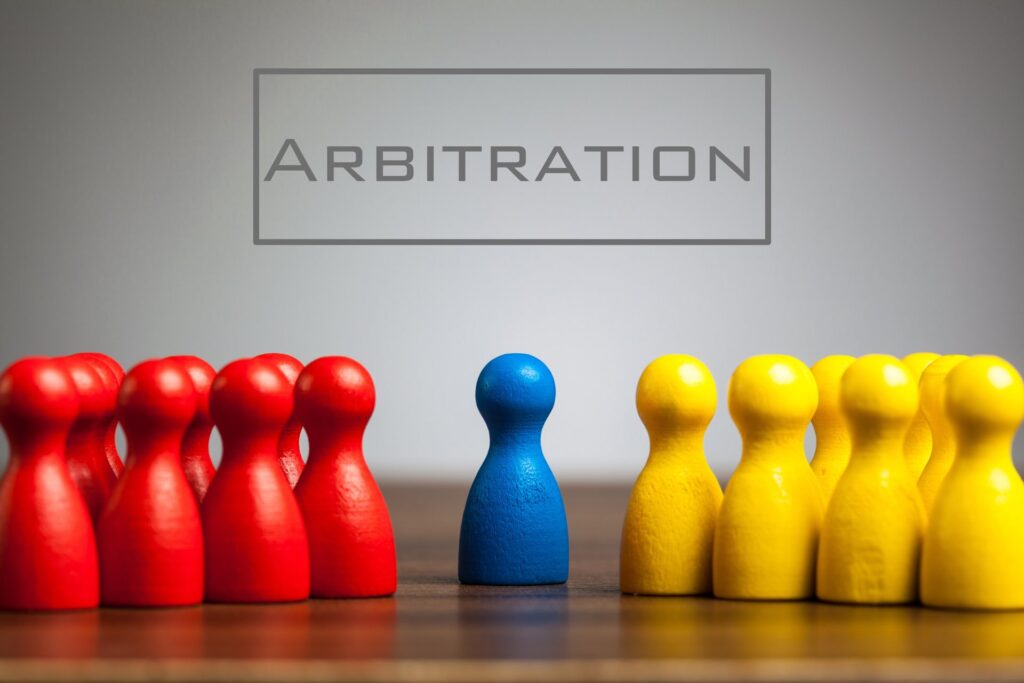 Pawns in multiple colors on a table with the word arbitration on the wall
