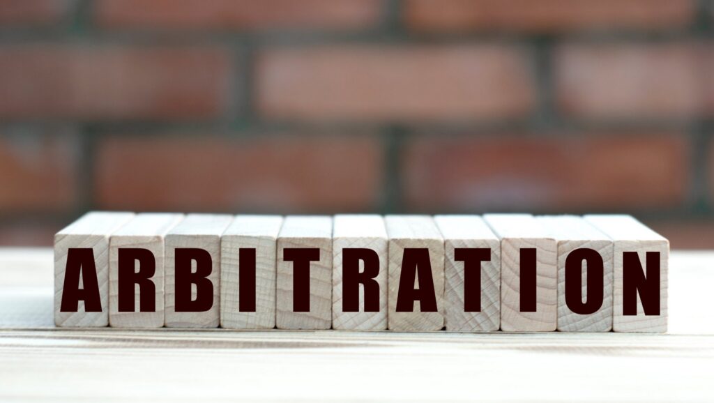 Wooden blocks that say arbitration with a brick background