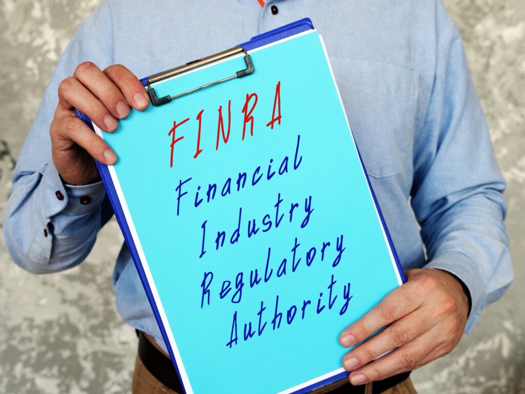 Person holding a clipboard that says FINRA Financial Industry Regulatory Authority