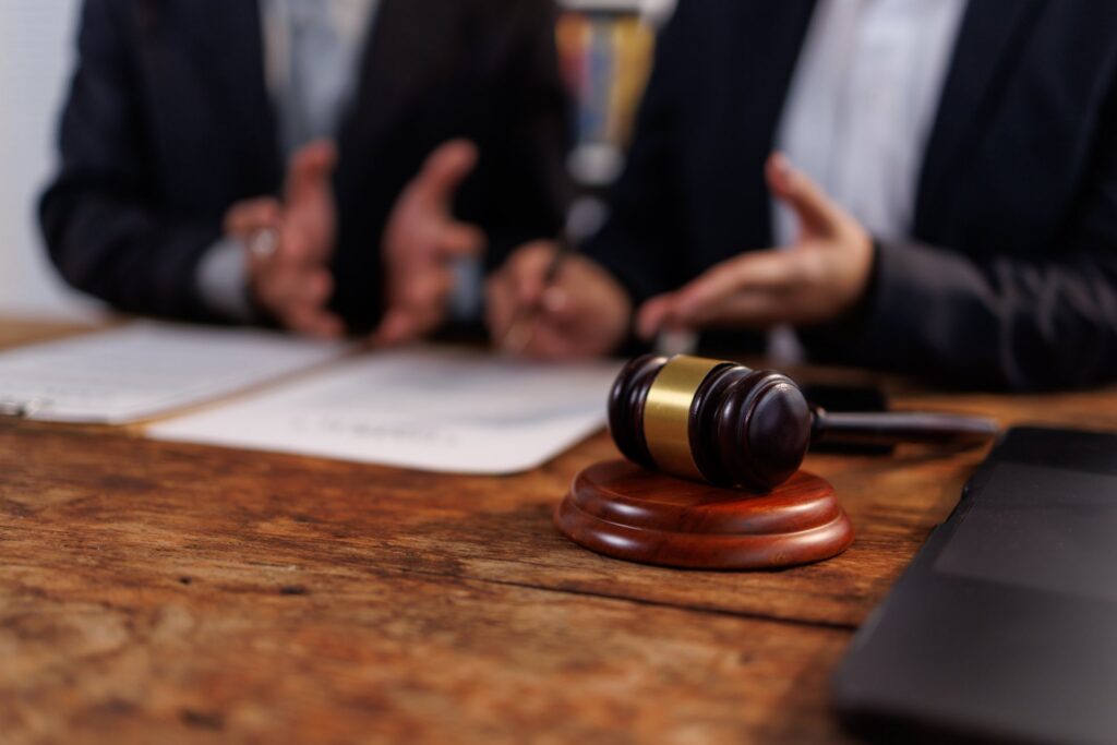 Two people sitting at a desk with a gavel on the table in front of them