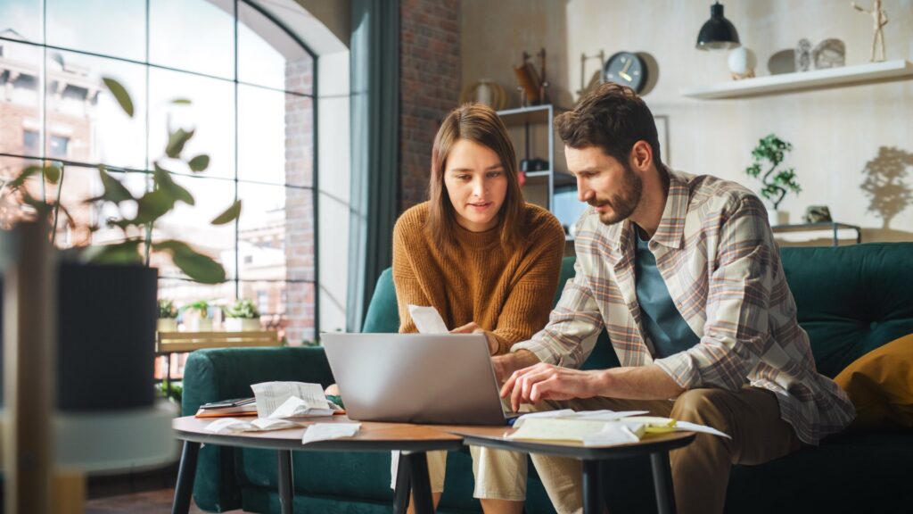 Two people sitting on a green couch on a laptop